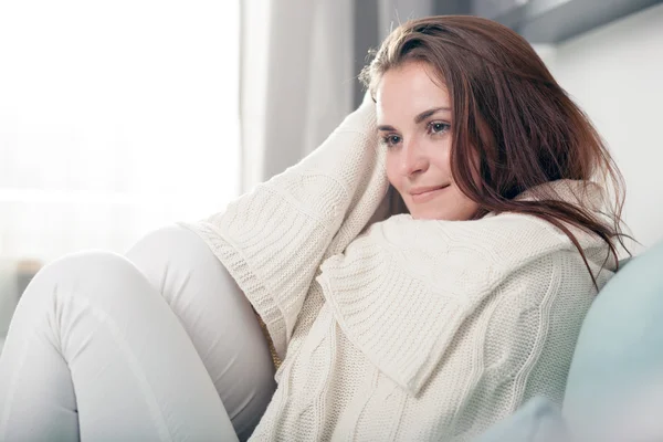 Szczęśliwa młoda kobieta, leżąc na kanapie i relaks w domu. Styl casual strzelać kryty — Zdjęcie stockowe