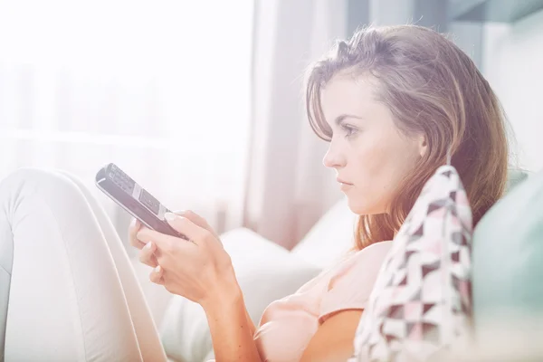 Junge Frau, die zu Hause auf der Couch sitzt und fernsieht. Gelegenheitsarbeit — Stockfoto