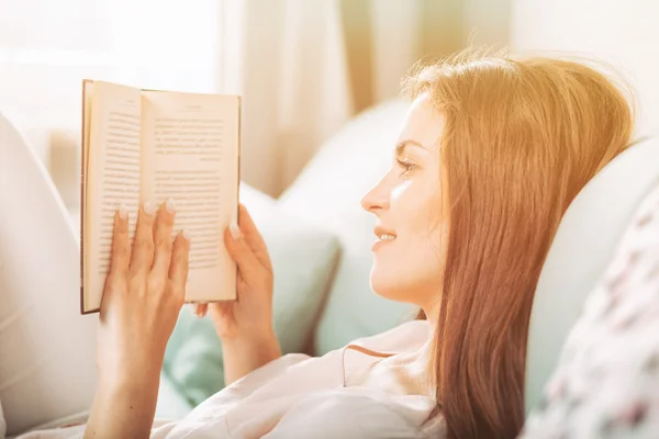 Fiatal nő feküdt a kanapén, és otthon egy könyvet olvas. Alkalmi st — Stock Fotó