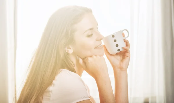 Porträtt av ung kvinna kopplar av hemma och dricker kaffe. Ca — Stockfoto