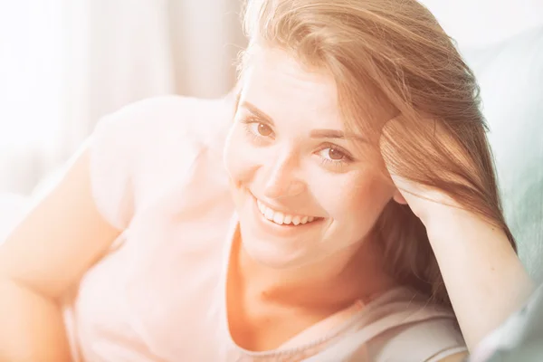 Happy young woman lying on couch at home and smiling. Casual sty — Stock Photo, Image