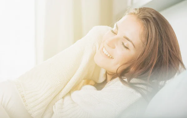 Mujer joven y feliz tumbada en el sofá y relajándose en casa. Casual st —  Fotos de Stock