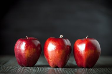 Ahşap masa koyu arka plan üzerinde kırmızı elma görünümü ön