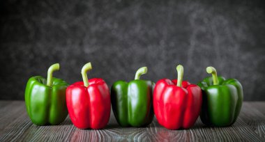 Ahşap tahtası koyu arka plan kopya alanı üzerinde kırmızı ve yeşil biber