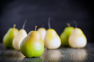 Ahşap masa koyu arka plan üzerinde yeşil armut görünümü ön