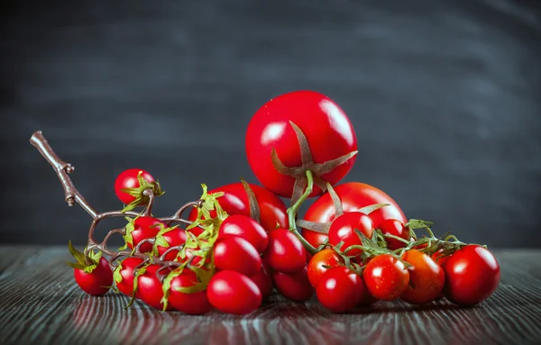 Vários tomates na mesa de madeira fundo escuro vista frontal — Fotografia de Stock