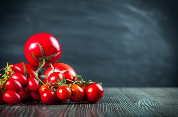 Vários tomates na mesa de madeira espaço de cópia de fundo escuro — Fotografia de Stock