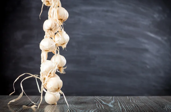Stringa di aglio su tavolo di legno scuro spazio di copia di sfondo — Foto Stock