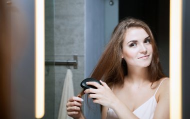 Bir banyo aynası önünde saç fırçalama kadın
