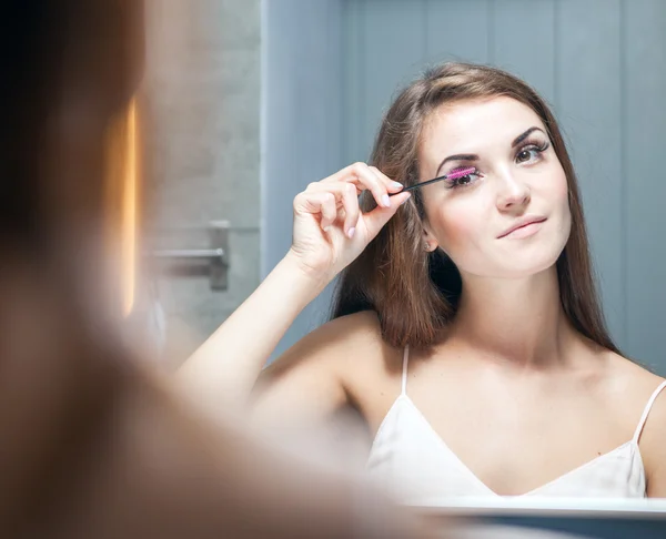 Frau trägt Wimperntusche auf langen Wimpern vor Spiegel auf — Stockfoto