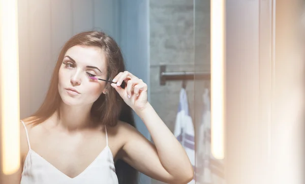 Frau trägt Wimperntusche auf langen Wimpern vor Spiegel auf — Stockfoto