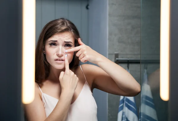 Bir banyo aynası önünde sivilce sıkma kadın — Stok fotoğraf