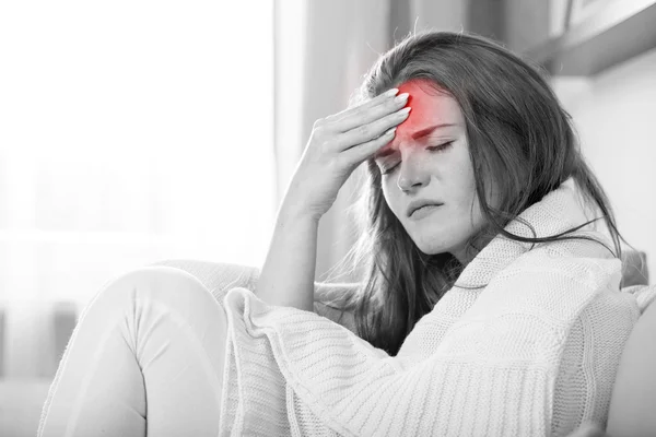 Mujer joven con dolor de cabeza tumbada en el sofá en casa. Estilo casual i — Foto de Stock