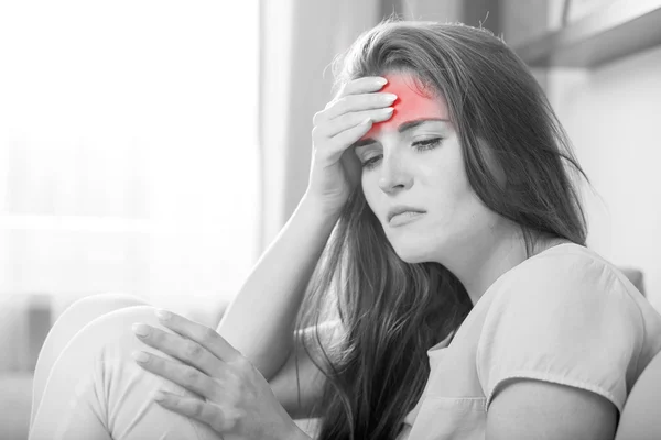 Mujer joven con dolor de cabeza tumbada en el sofá en casa. Estilo casual i — Foto de Stock