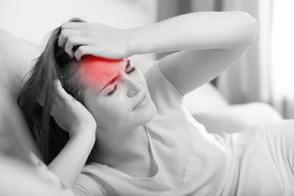 Junge Frau mit Kopfschmerzen, die zu Hause auf dem Sofa liegt. lässiger Stil — Stockfoto