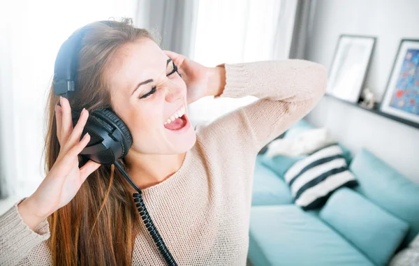 Mulher com fones de ouvido cantando e ouvindo música em casa — Fotografia de Stock