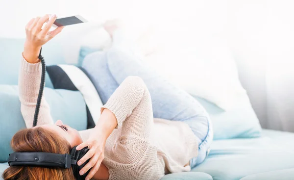Žena s sluchátka ležet a poslouchat hudbu doma — Stock fotografie