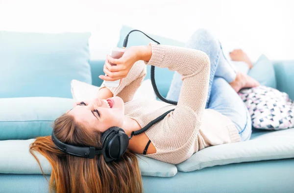 Vrouw met hoofdtelefoon zingen en luisteren naar muziek thuis — Stockfoto