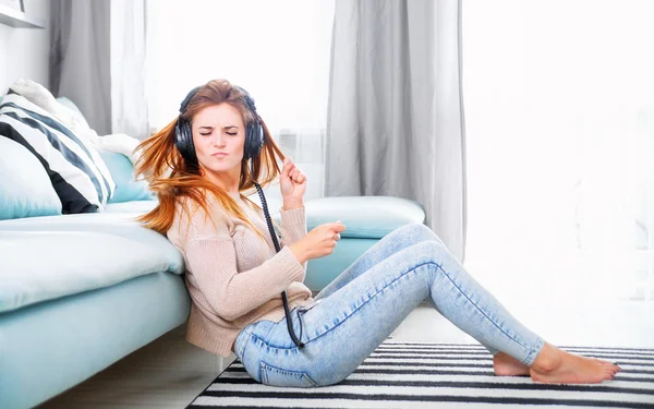 Vrouw met koptelefoon luisteren naar muziek thuis — Stockfoto