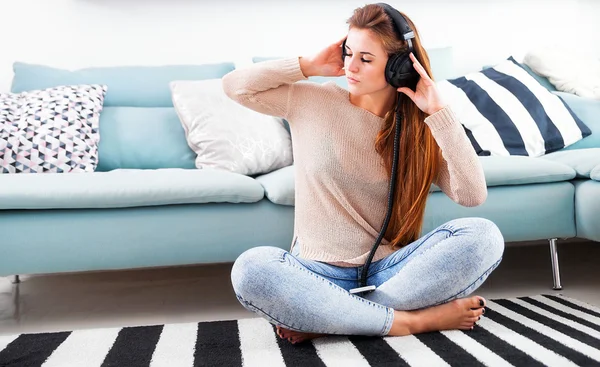 Женщина в наушниках слушает музыку дома — стоковое фото