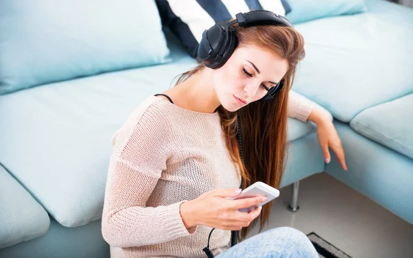 Vrouw met koptelefoon luisteren naar muziek thuis — Stockfoto