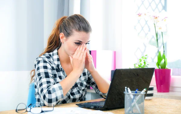 Stressed and thinking woman in home office using laptop