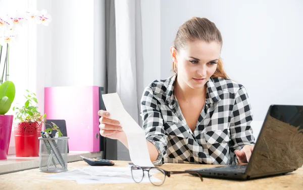 Lachende vrouw berekenen en betalen van rekeningen in kantoor aan huis — Stockfoto