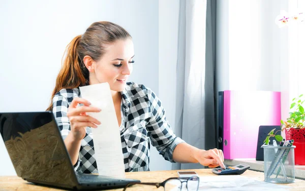 Mulher sorridente calculando e pagando contas no escritório em casa — Fotografia de Stock