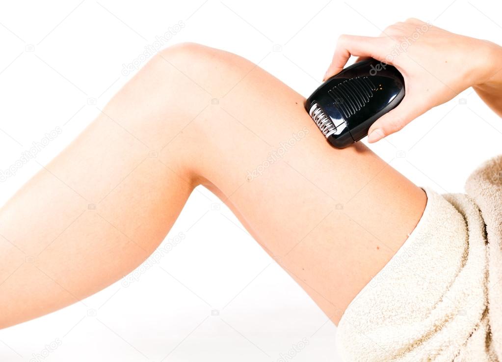 Woman shaving legs with electric shaver depilator