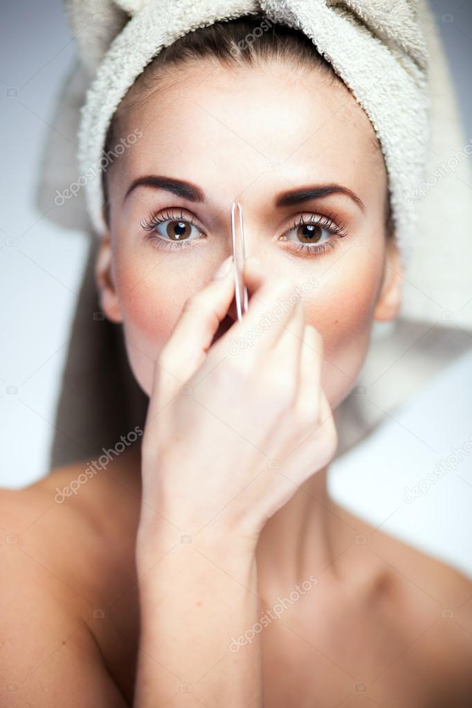 Fresh model girl shaping eyebrows with tweezer