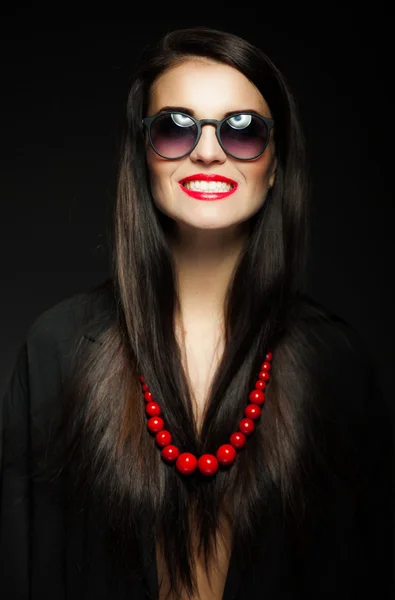 Glamour fille aux cheveux longs brillants foncés, lunettes de soleil et perles rouges — Photo