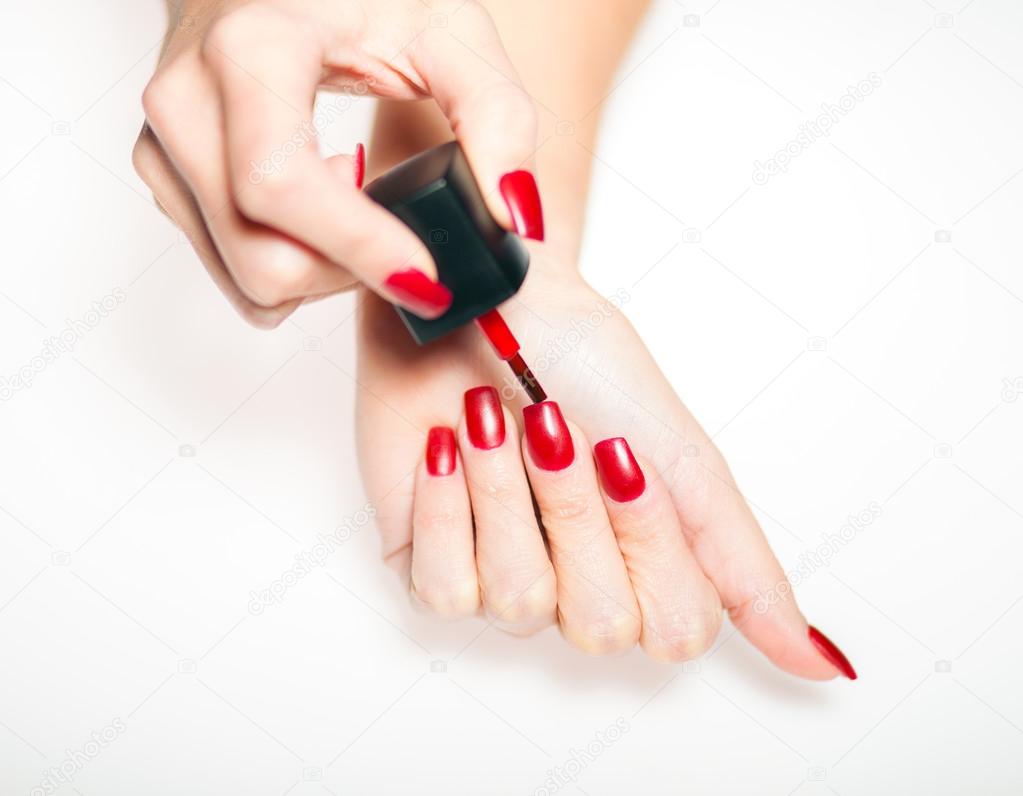 Red manicure nail polish painting nails on bright background