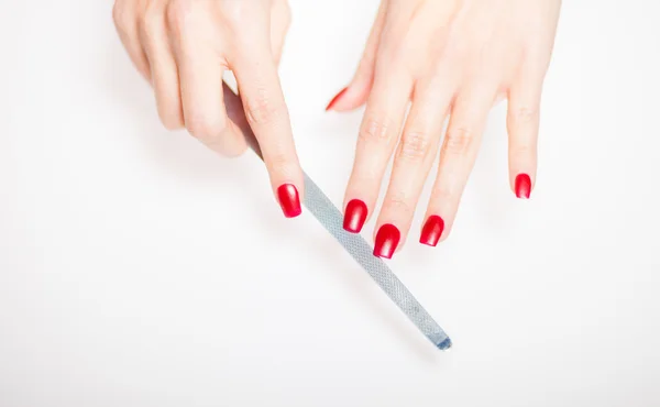 Маникюр женской руки с пилкой для ногтей на ярком фоне — стоковое фото