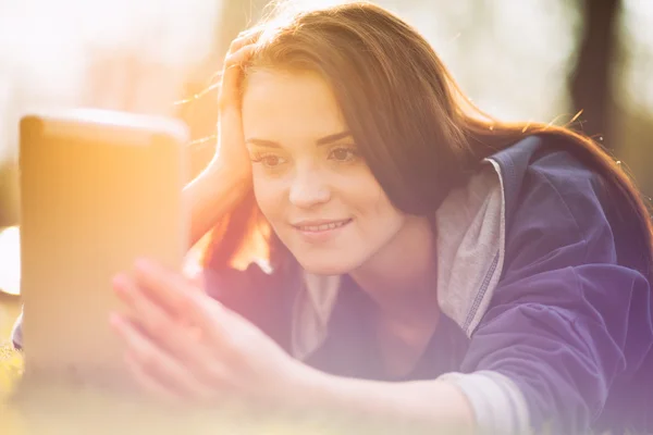 Hermosa chica con tableta o ebook al aire libre puesta en el campo —  Fotos de Stock