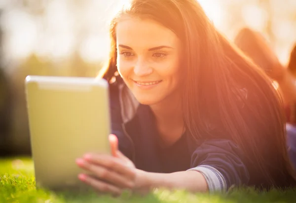 Hermosa chica con tableta o ebook al aire libre puesta en el campo —  Fotos de Stock