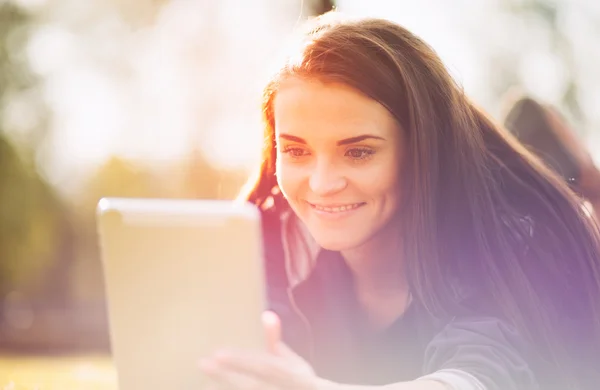 Hermosa chica con tableta o ebook al aire libre puesta en el campo — Foto de Stock