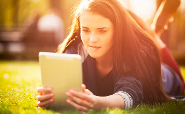 Hermosa chica con tableta o ebook al aire libre puesta en el campo —  Fotos de Stock