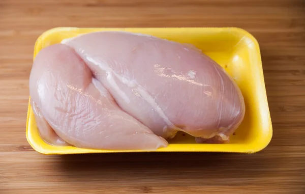 Filetes de pechuga de pollo crudo en paquete sobre tabla de madera — Foto de Stock