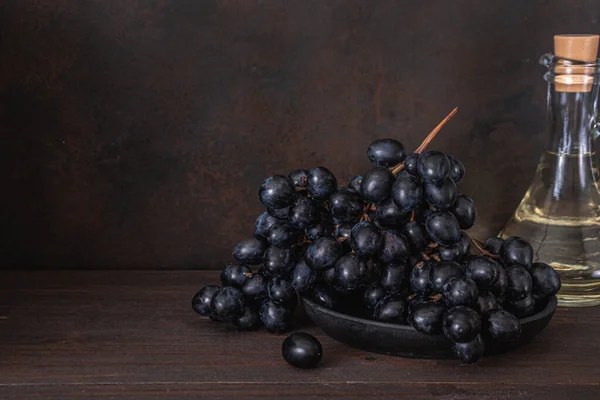 Fresh Dark blue purple grape on plate on wooden table over dark background. Wine grapes, table grapes. Exotic fruit. Top view