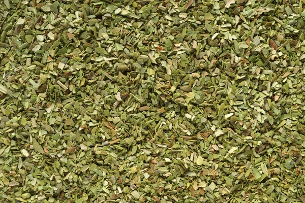Pile of dried green oregano texture or background close-up macro shot.