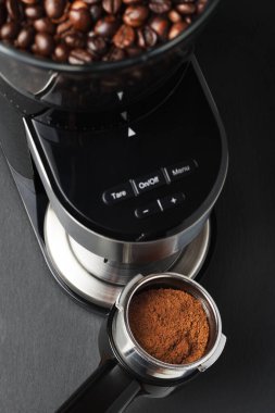 Elektrikli öğütücüden portafilter tutacağına öğütülmüş kahve dökülüyor.