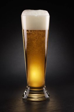 Siyah arka planda köpük kapaklı taze biralı kupa..