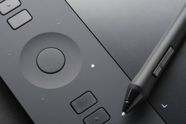 Cihazın yüzeyinde kalem olan grafiksel tablet, yakın plan fotoğraf. İllüstratörler, tasarımcılar, rötuşcular için profesyonel araç.