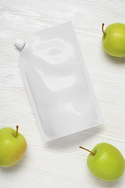 木製のテーブルの上にリンゴと白いプラスチック製のポーチバッグ デザインのためのモックアップテンプレート 3Dレンダリング図 — ストック写真