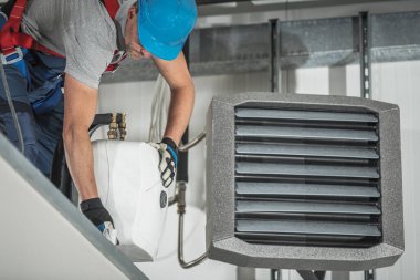 Su ısıtma cihazının kurulumu Depo binasının içinde, iç ısıtıcının yanında. HVAC Teknisyeni.