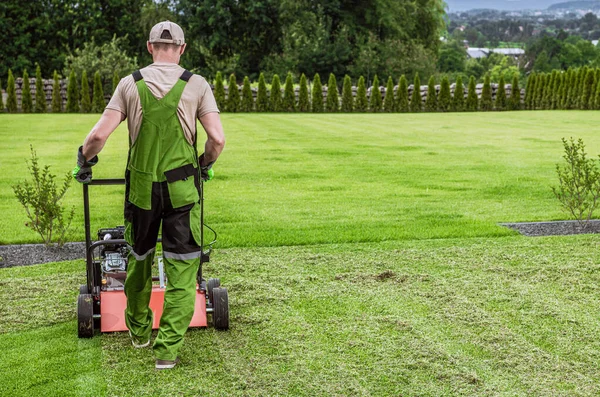 Caucasian Gardener in His 40s and His Powerful Gasoline Lawn Aerator Job For Controlling Lawn Thatch, And Reducing Soil Compaction. Garden Technologies.
