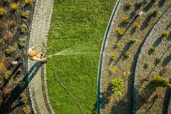 园艺与园林绿化产业主题 40多岁的白人花园工人在新开发的住宅花园中浇灌新的天然草皮 空中视图 — 图库照片