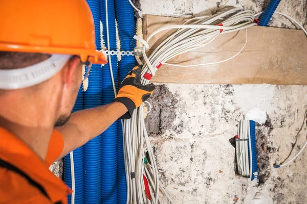 橙色硬帽 身穿高加索电工40多岁移动的电线束在新开发的商业大楼内 建筑和电力工业 — 图库照片