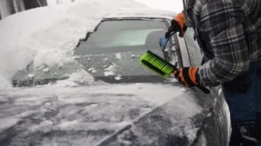 Sürücü, kar ve buzu arabasının ön camından kaldırıyor