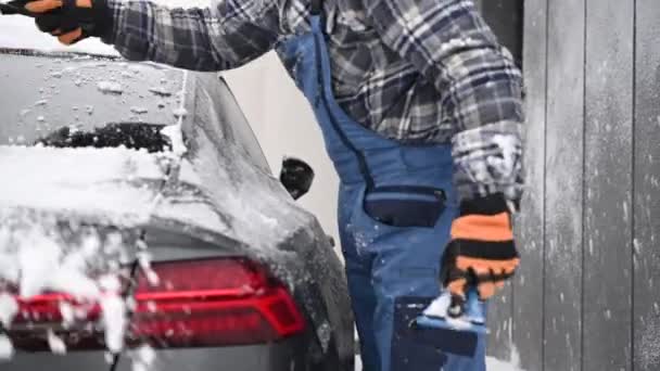寒い冬の間に雪と氷から現代の車を掃除する男性 — ストック動画
